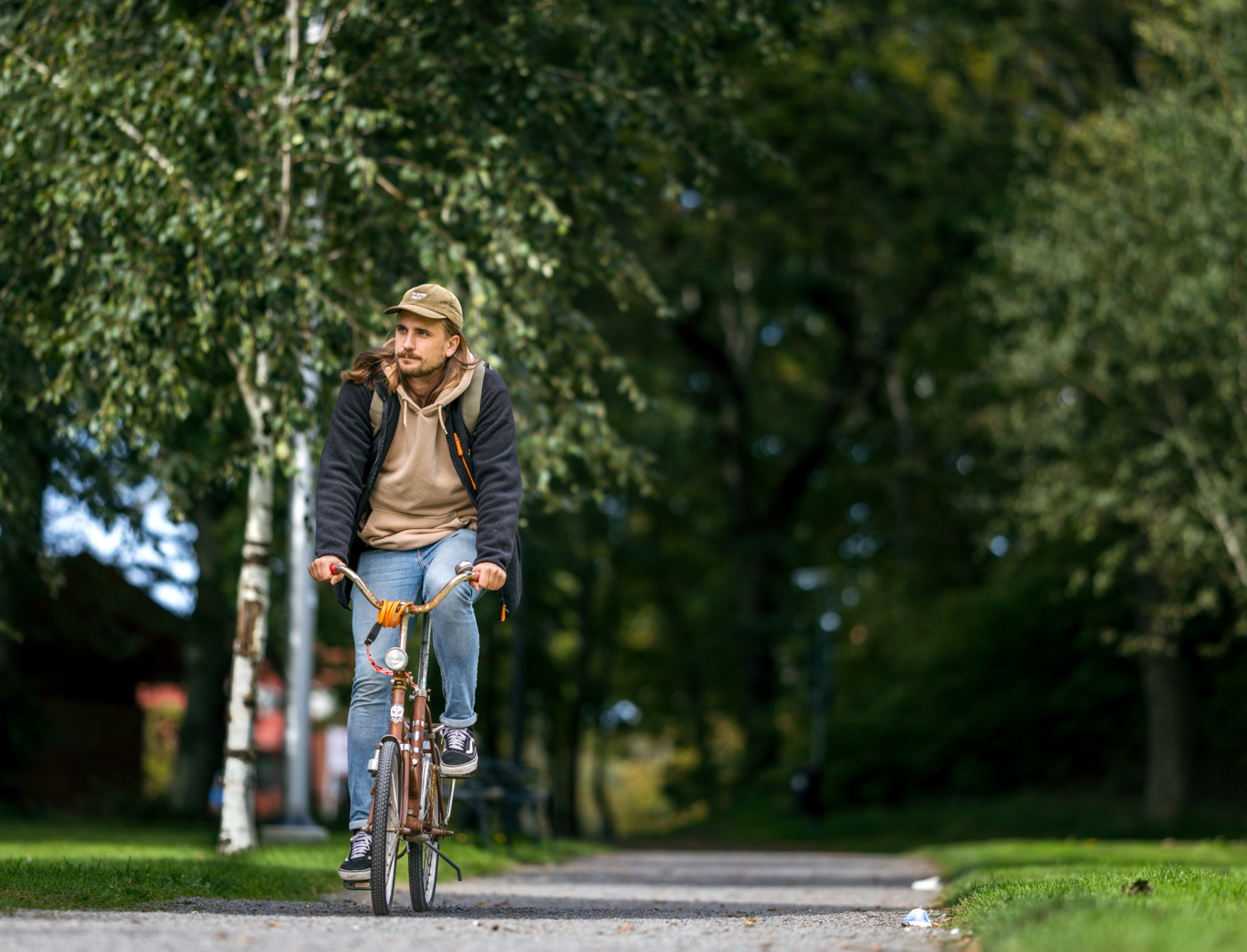 Ung, leende man cyklar i en grönskande omgivning i Höganäs
